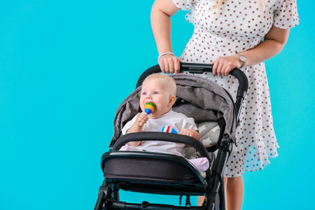 Woman and her cute baby in stroller on color background