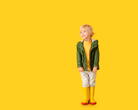 Cute little boy in autumn clothes on color backgroundの写真素材