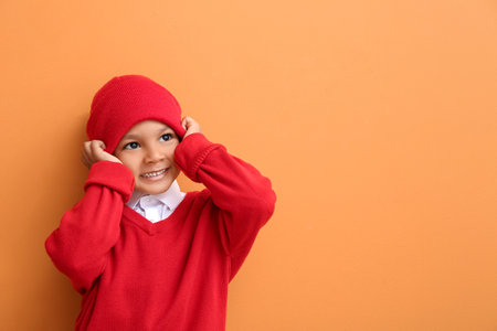 Cute African-American boy in warm hat on color background