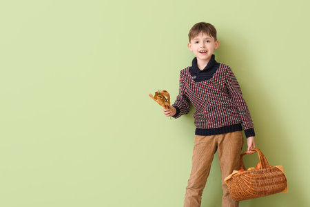 Cute little boy holding basket of apples on color background