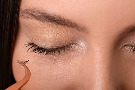 Beautiful young woman applying fake eyelashes, closeupの写真素材
