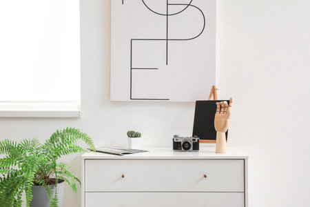 Wooden hand and photo camera on chest of drawers in interior of room