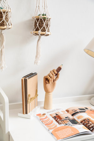 Wooden hand with pencil on table in interior of room