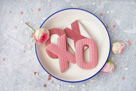 Plate with tasty cookies, rose flowers and sprinkles on light background. Valentine's Day celebrationの写真素材