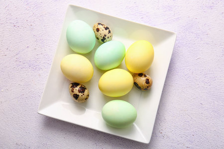 Plate with natural and painted Easter eggs on light backgroundの写真素材