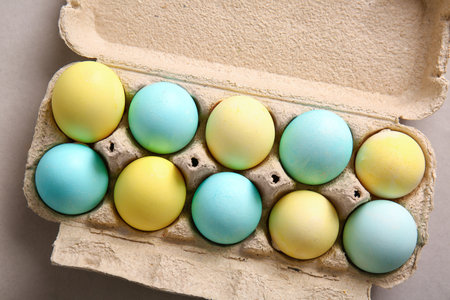 Cardboard holder with painted Easter eggs on gray background, closeup