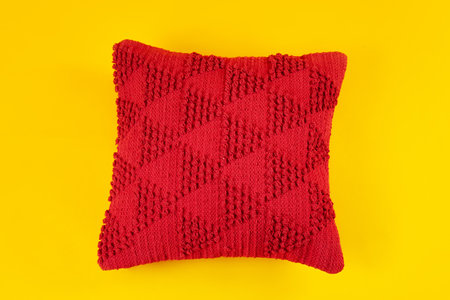 Red decorative pillow on yellow backgroundの写真素材