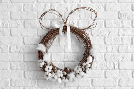 Easter wreath with cotton flowers and quail eggs on white brick wallの写真素材