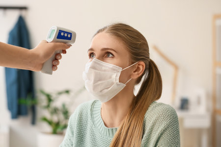 Measuring of woman's temperature in office. Coronavirus epidemic