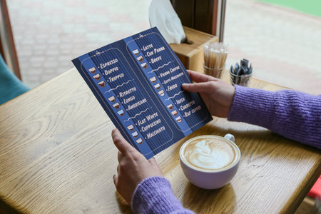 Woman with menu and cup of hot coffee in cafe