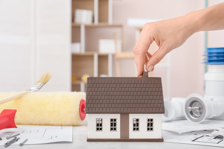 Female hand with model of new house on tableの写真素材
