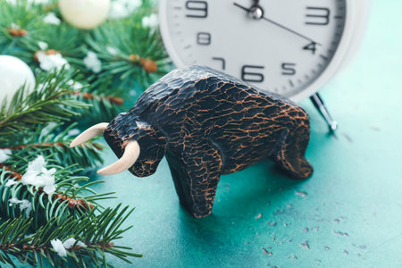 Figurine of bull, clock and New Year decor on color background