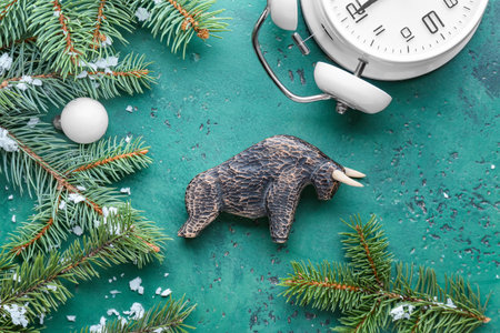 Figurine of bull, clock and New Year decor on color background