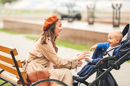 Woman and her cute baby in stroller outdoors