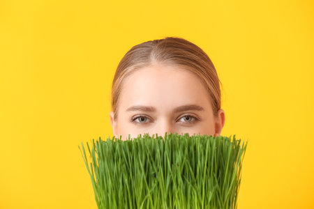 Young woman with wheatgrass on color backgroundの写真素材