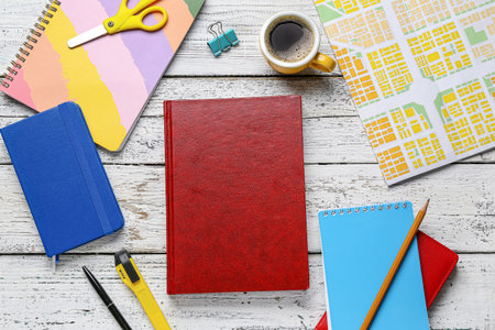 Blank book, cup of coffee and stationery on wooden background