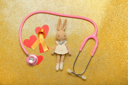 Toy, stethoscope, red hearts and golden ribbon on color background. Childhood cancer awareness conceptの写真素材