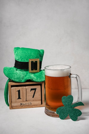 Glass of beer, calendar with date of St. Patrick's Day, Leprechaun hat and clover on light...