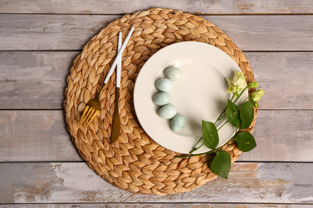 Table serving with Easter eggs and eustoma flowers on gray wooden background