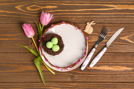 Table serving with Easter eggs and tulip flowers on brown wooden backgroundの写真素材