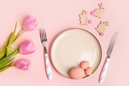 Table serving with Easter eggs and tulip flowers on pink backgroundの写真素材