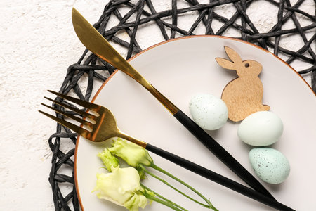 Table setting with Easter eggs, cutlery and eustoma flowers on white grunge background