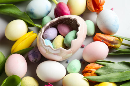 Composition with painted Easter eggs and beautiful tulip flowers on white background, closeup