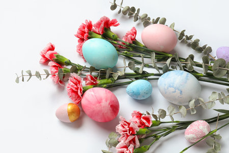 Composition with painted Easter eggs, carnation flowers and eucalyptus branches on white background, closeupの写真素材