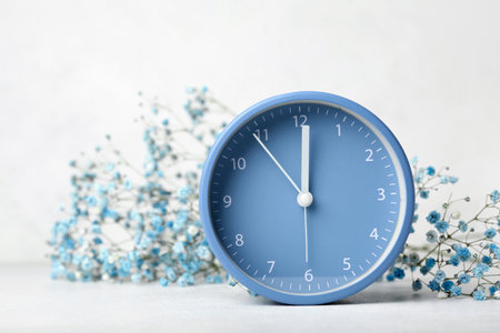 Alarm clock and beautiful gypsophila flowers on light backgroundの写真素材