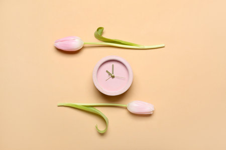 Alarm clock and beautiful tulip flowers on color background