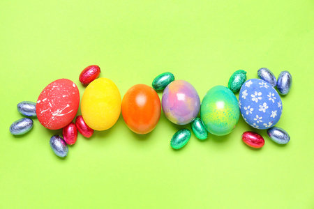 Composition with painted Easter eggs and candies on green backgroundの写真素材