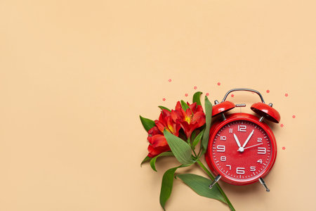 Composition with alarm clock and beautiful alstroemeria flowers on color backgroundの写真素材