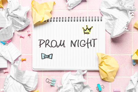 Notebook with text PROM NIGHT, crumpled paper, clips and chalks on pink tile backgroundの写真素材