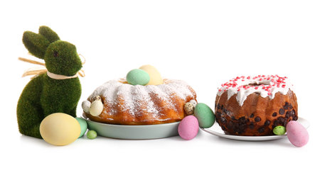 Plates with tasty Easter cakes, eggs and toy bunny on white backgroundの写真素材