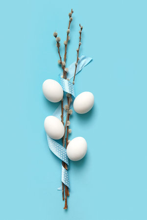 Composition with willow branches, ribbon and Easter eggs on color backgroundの写真素材