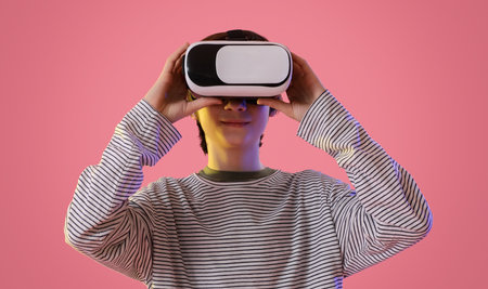 Teenage boy in VR glasses on pink background, closeupの写真素材