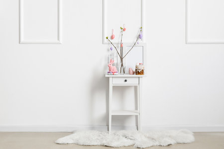 Beautiful Easter decor, cake and jug of water on table near light wallの写真素材