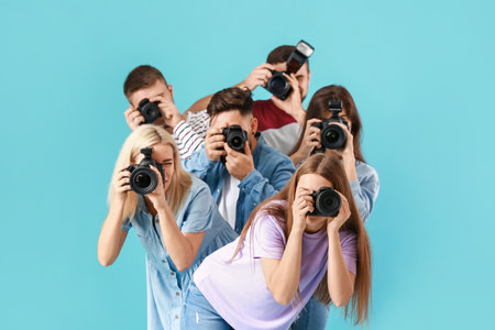Group of young photographers on color background