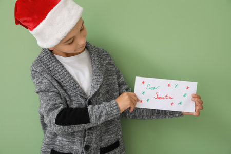Little boy with letter to Santa on color backgroundの写真素材
