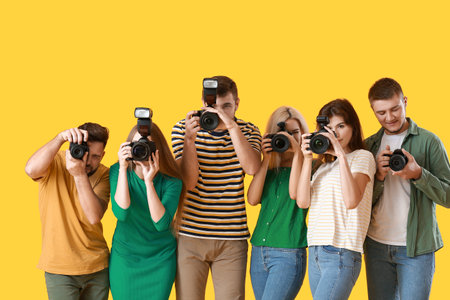 Group of young photographers on color background