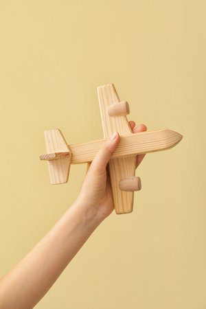 Female hand with wooden airplane on color backgroundの写真素材