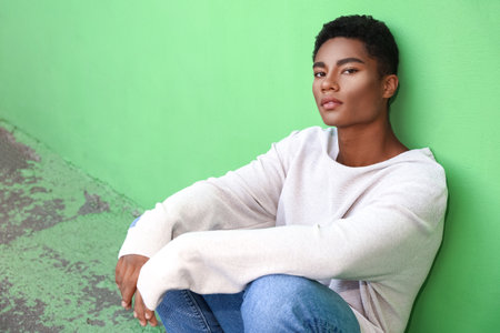 Stylish young African-American man near color wall