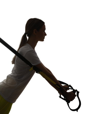 Silhouette of sporty young woman training with TRX straps on white backgroundの写真素材