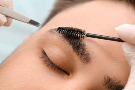 Young man undergoing eyebrow correction procedure in beauty salon, closeupの写真素材