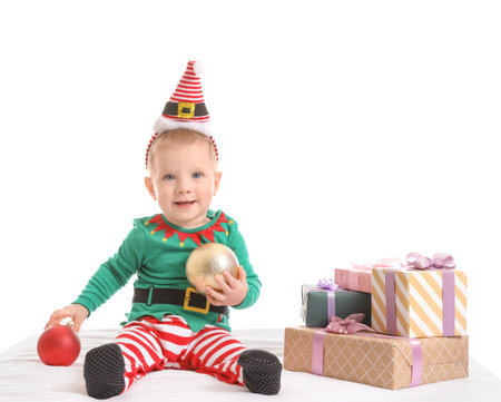 Cute little baby in Christmas elf costume and with gifts on white backgroundの写真素材