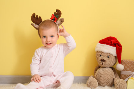 Cute little baby with toy and Christmas gifts near color wallの写真素材