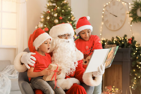 African-American Santa Claus with cute children reading book at home on Christmas eveの写真素材