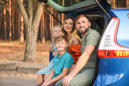 Happy family sitting in car trunk outdoorsの写真素材