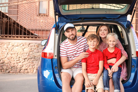 Happy family sitting in car trunk outdoorsの写真素材