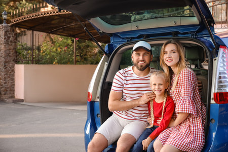 Happy family sitting in car trunk outdoorsの写真素材